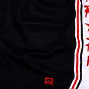 Close-up of a black athletic mesh jersey with a vertical white side stripe outlined in red and a small red logo near the bottom.