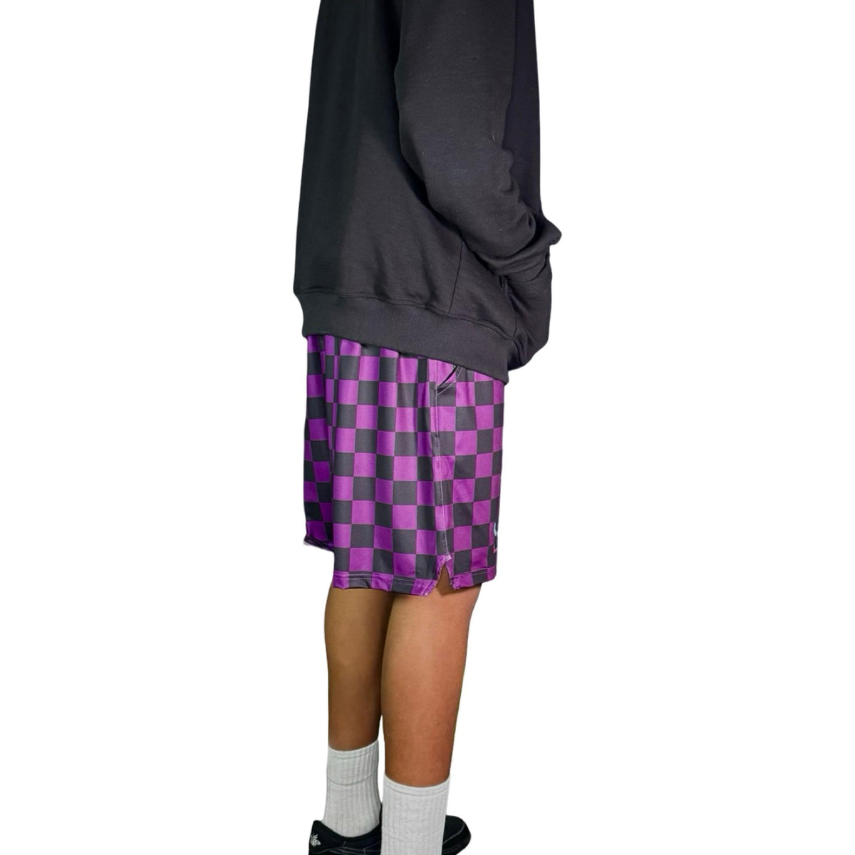 Person wearing a dark hoodie and purple checkered shorts 