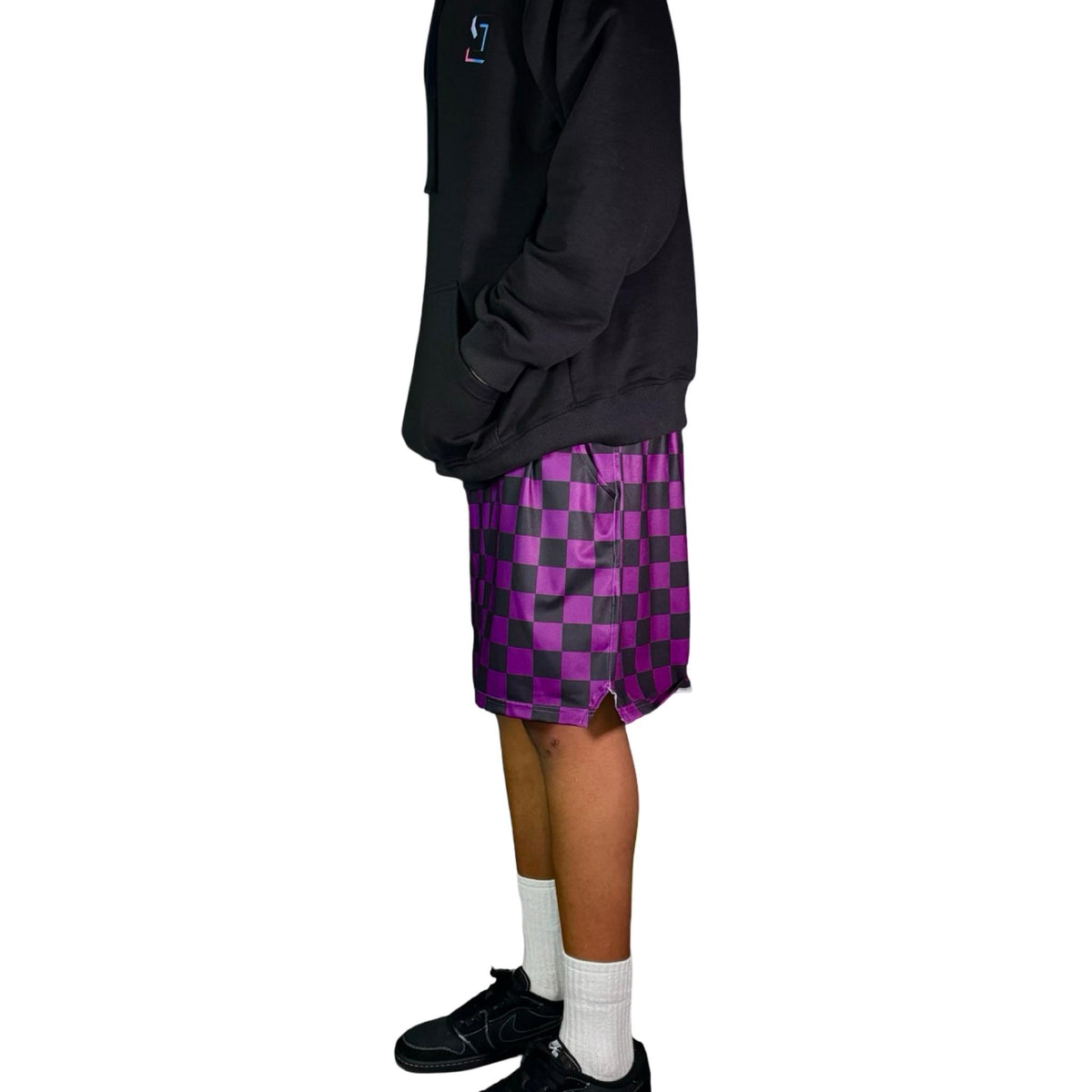 Person wearing a black hoodie and purple checkered shorts