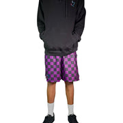 Person wearing a black hoodie and purple checkered shorts on a white background
