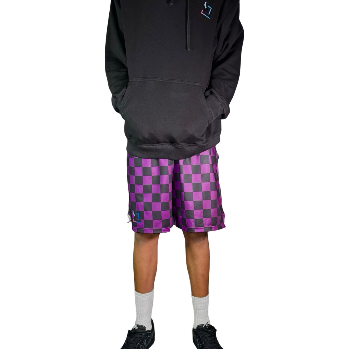 Person wearing a black hoodie and purple checkered shorts on a white background