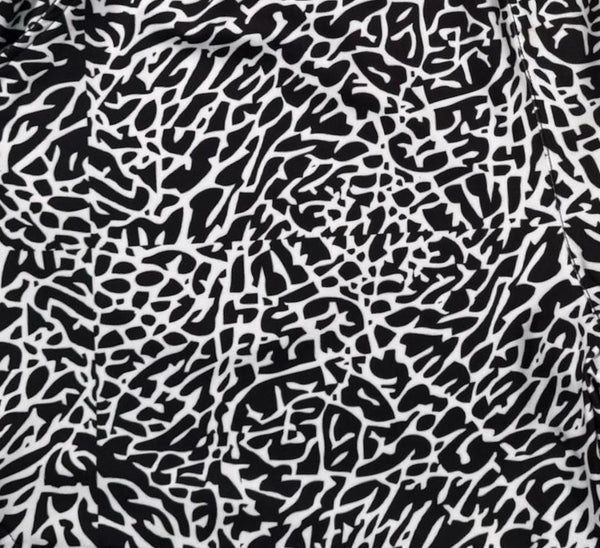 Closeup view of texture of Black and white elephant print pattern soft dry fit shorts on a white background
