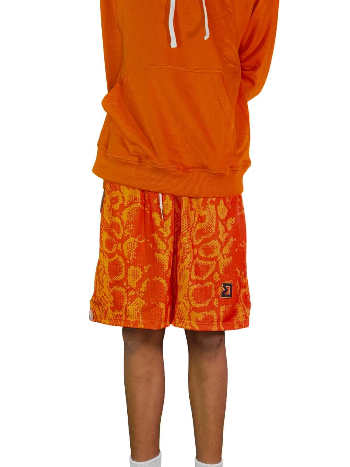 Neon orange snakeskin pattern mesh shorts on male model