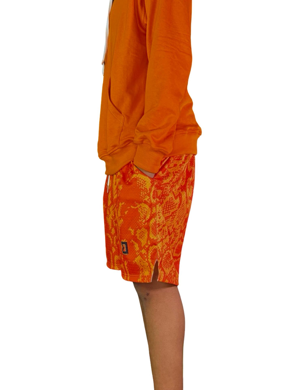 Neon orange snakeskin pattern mesh shorts on male model