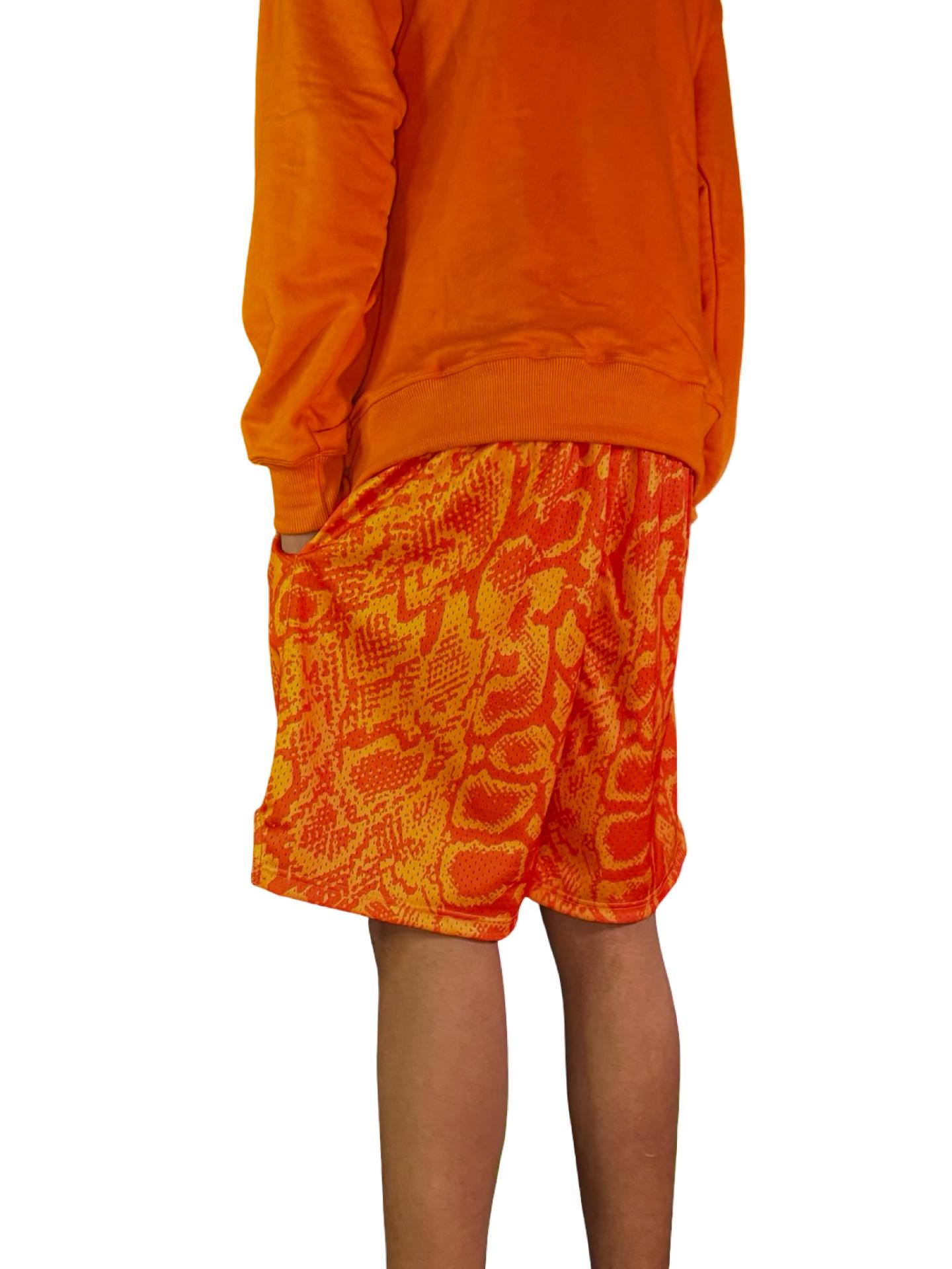 Neon orange snakeskin pattern mesh shorts on male model