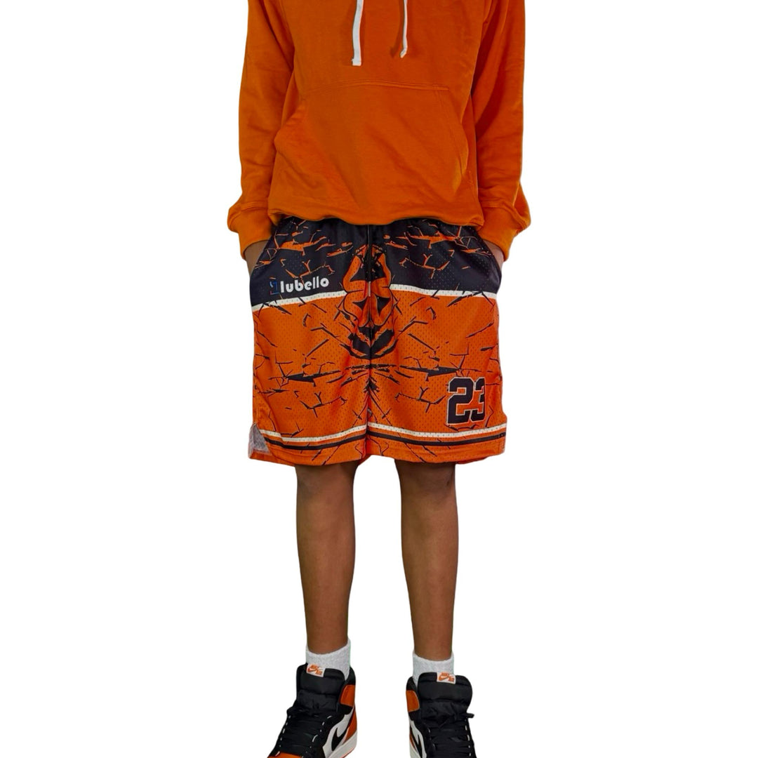 Person wearing an orange hoodie and shorts with a visible brand logo on a white background