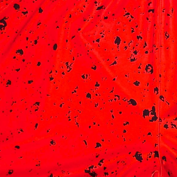 Closeup texture view of Red soft dry fit basketball shorts with black speckle repeating pattern on a white background