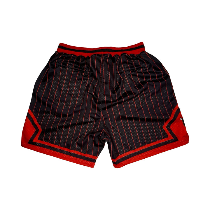 Black basketball shorts with thin red pinstripes, red side panels, and a red waistband, shown flat on a white background.