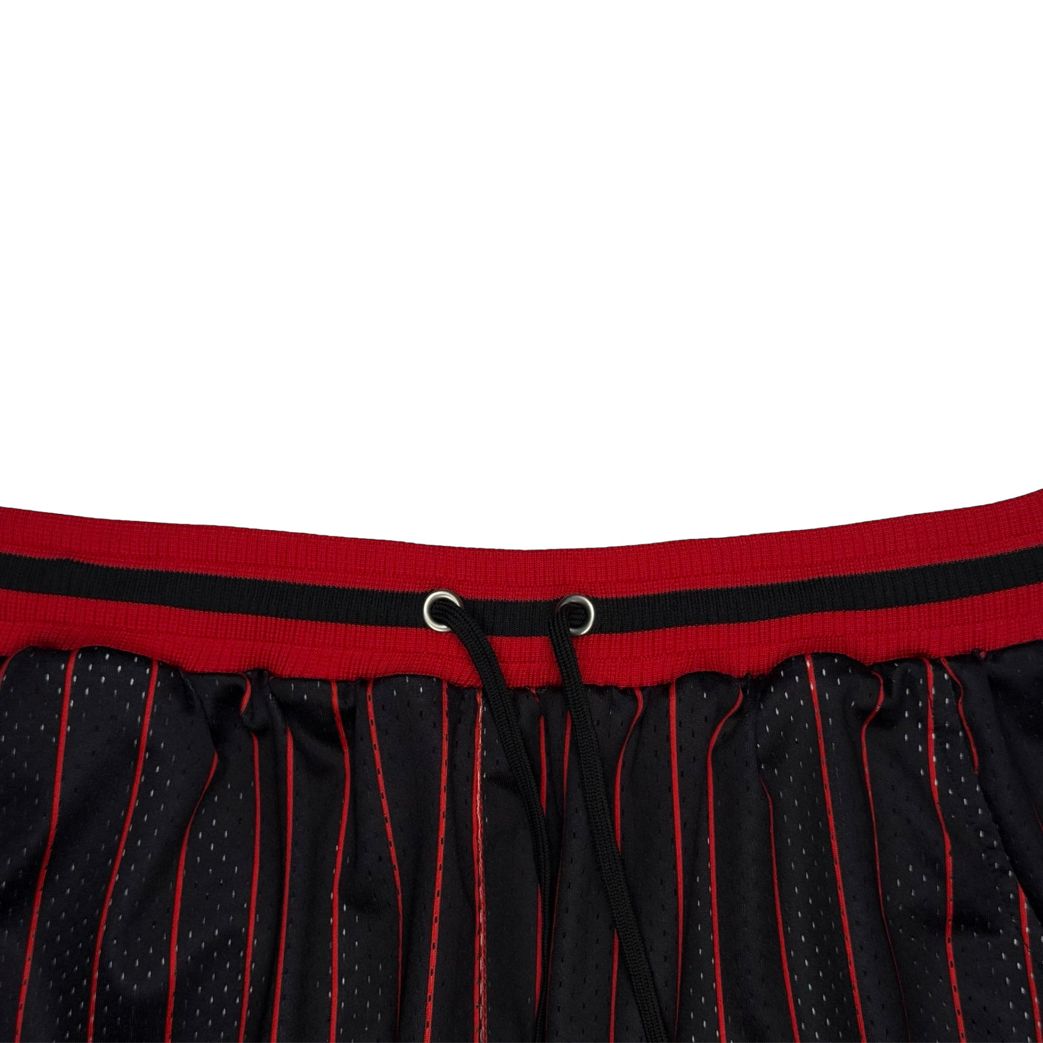Close-up of a black mesh athletic skirt with red pinstripes and a red waistband featuring a black stripe and drawstring.