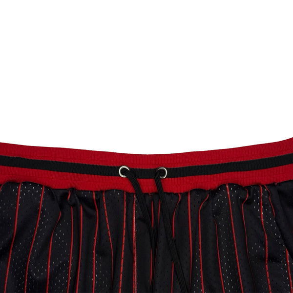 Close-up of a black mesh athletic skirt with red pinstripes and a red waistband featuring a black stripe and drawstring.