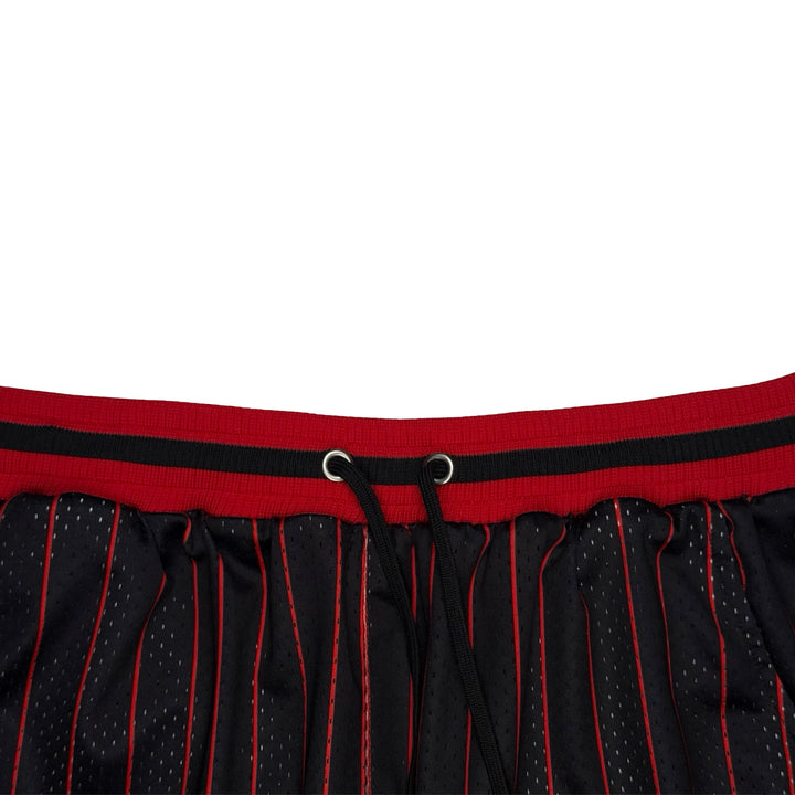 Close-up of a black mesh athletic skirt with red pinstripes and a red waistband featuring a black stripe and drawstring.