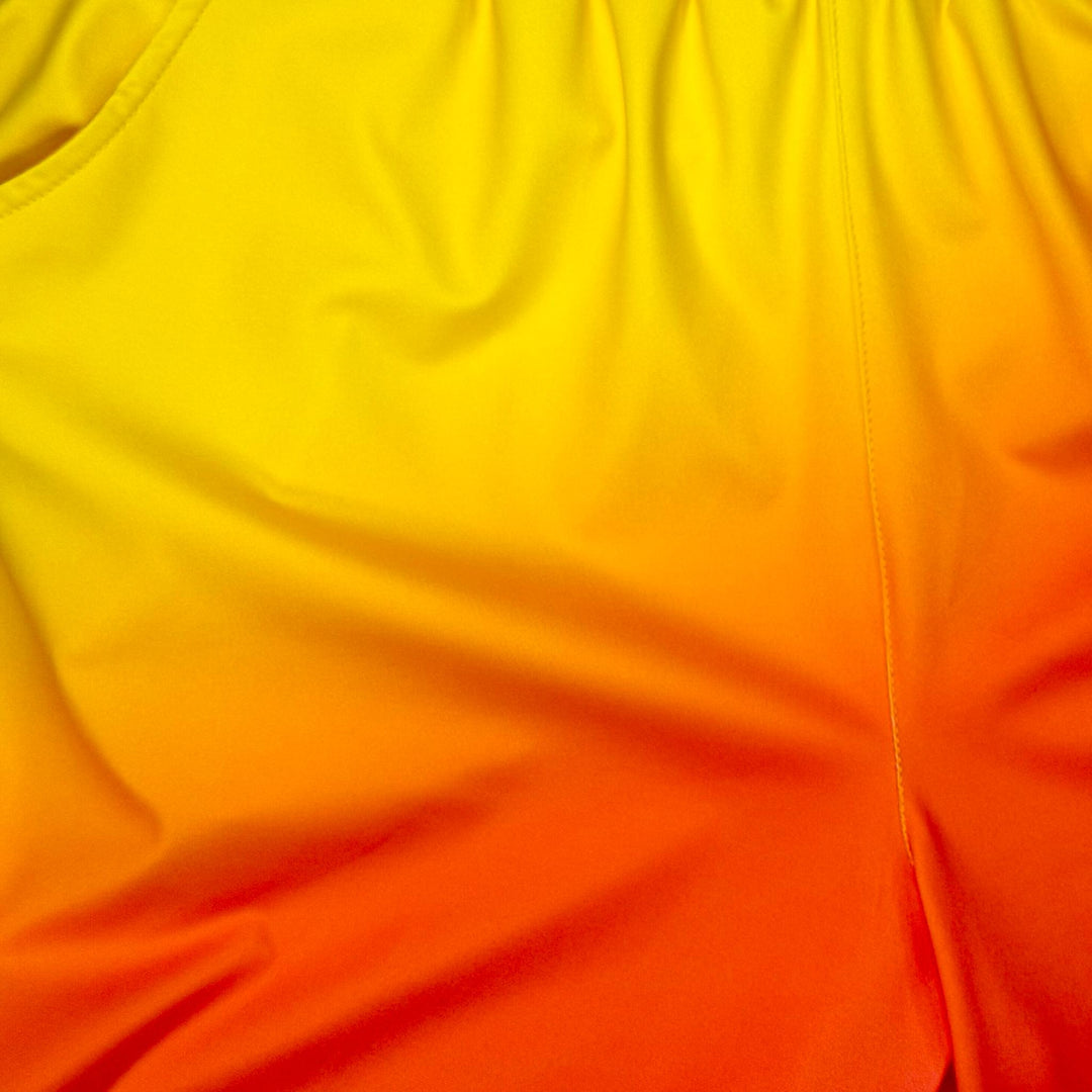 Close up texture view of Sunburst yellow to pink gradient dry fit shorts with yellow stripe on white background.