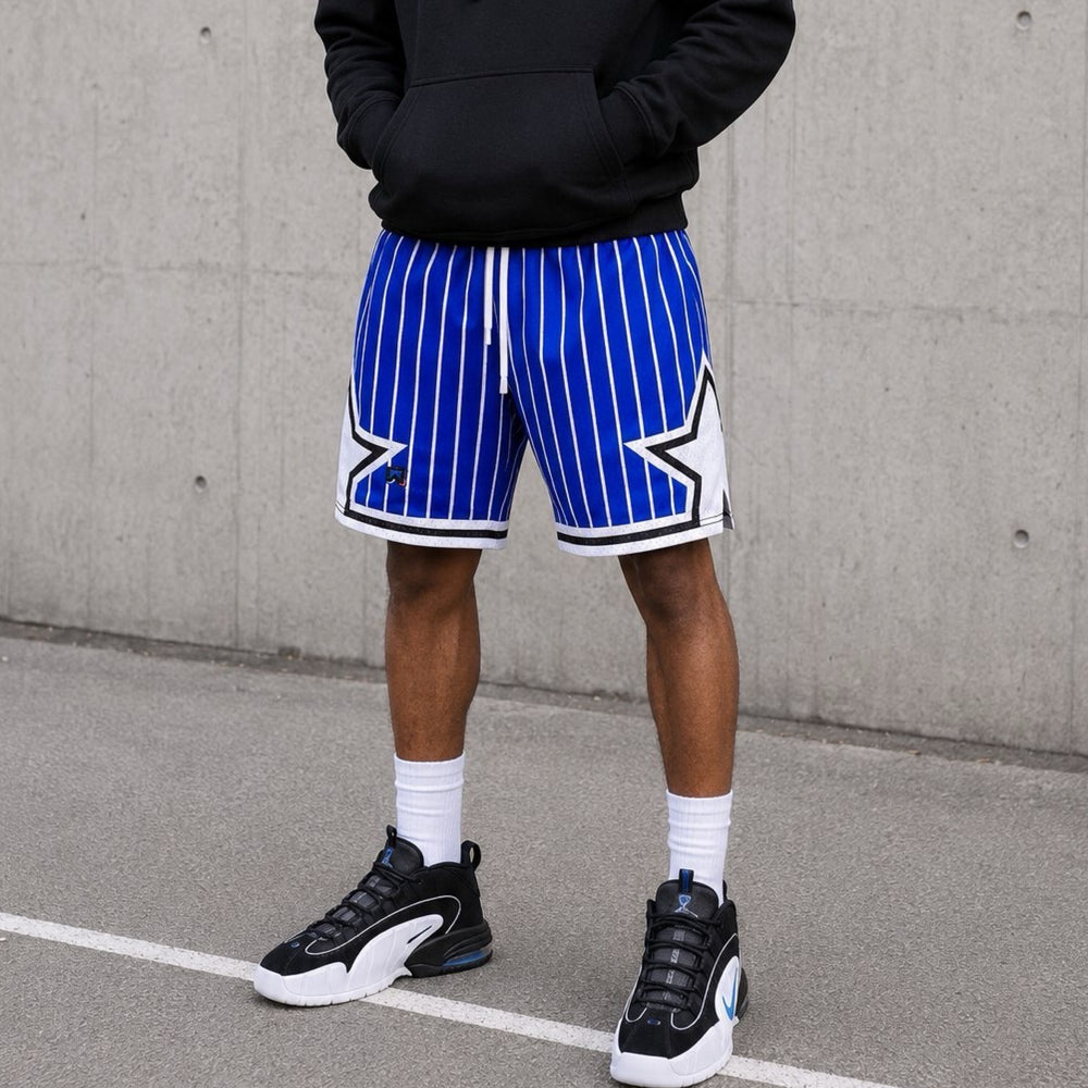 Person wearing blue and white striped shorts with a star design, standing against a concrete wall.