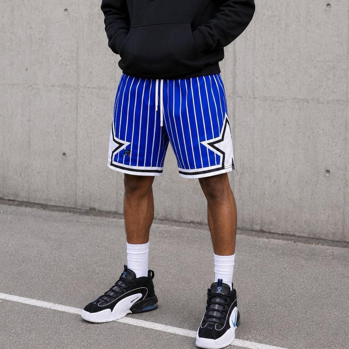 Person wearing blue and white striped shorts with a star design, standing against a concrete wall.