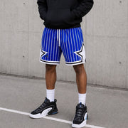 Person wearing blue and white striped shorts with a star design, standing against a concrete wall.