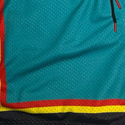 Close-up of a teal mesh athletic shorts fabric with a red and yellow side border, a red and yellow hem band, and a black mesh section at the bottom.