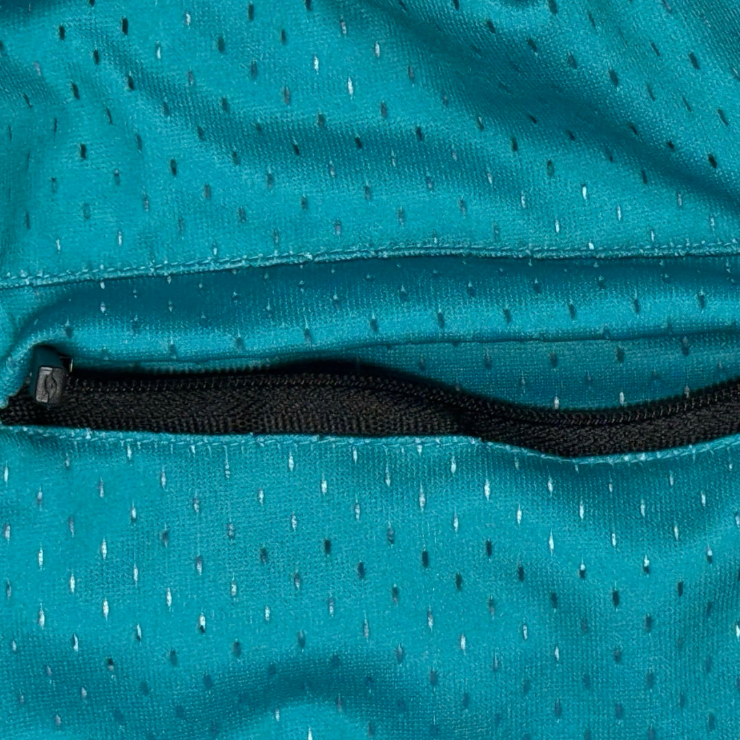 Close-up of a teal mesh fabric with a black zipper pocket.