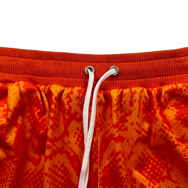 Mamba Elite PRO™ orange basketball shorts featuring a bold snakeskin-inspired pattern, premium MeshX™ construction, oversized PRO waistband, and performance athletic fit designed to match Kobe and Jordan sneakers.