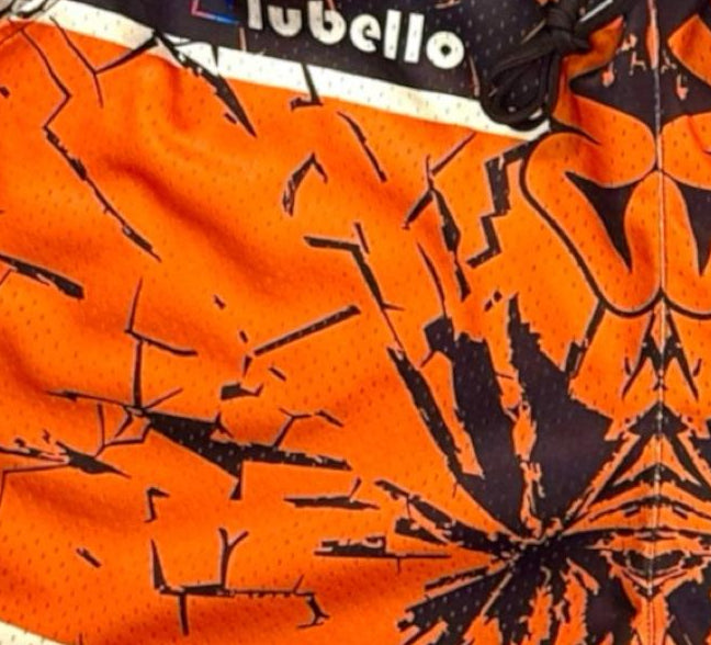Close-up of an orange and black sports mesh shorts with visible shattered backboard design.