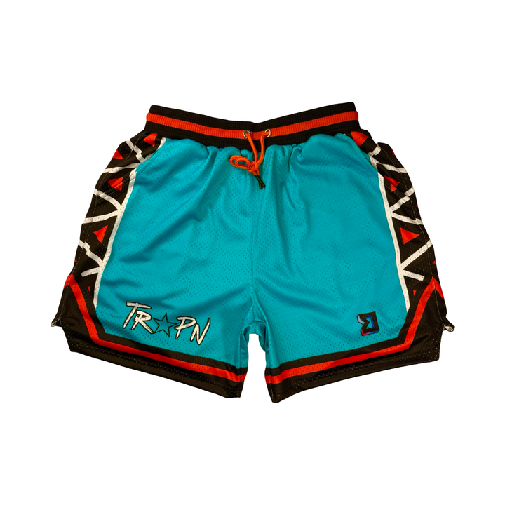 Trap Star Mesh Pro basketball shorts in aqua blue with tribal-style black/orange detailing, 2-inch pro waistband, and signature TR✶PN script by Trap’N Shorts.