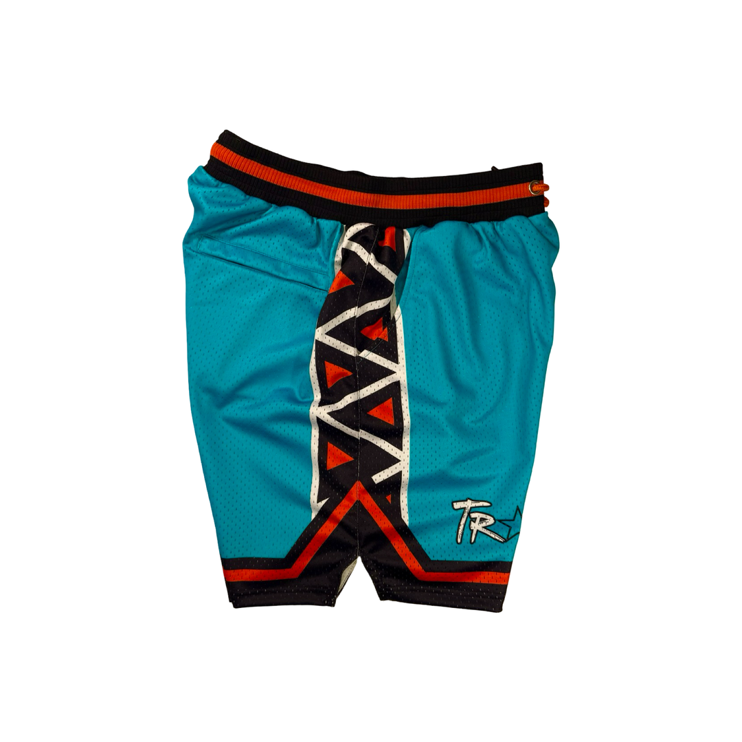 Trap Star Mesh Pro basketball shorts in aqua blue with tribal-style black/orange detailing, 2-inch pro waistband, and signature TR✶PN script by Trap’N Shorts.
