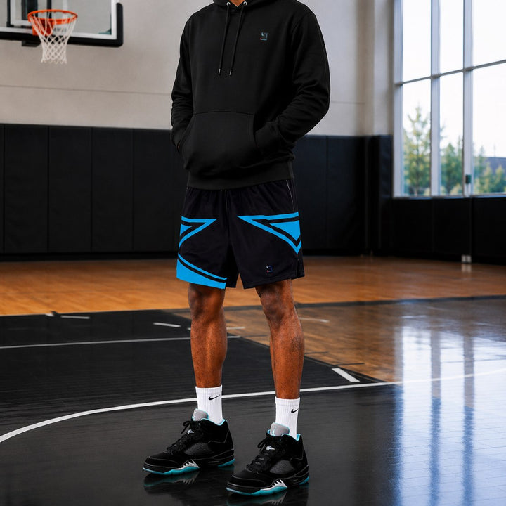 Person wearing a black hoodie and black and sky blue shorts on a basketball court